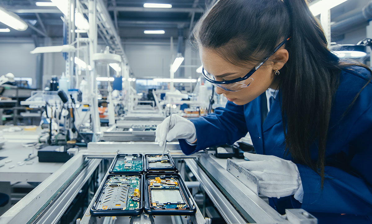 Shot of an Electronics Factory Workers Assembling Circuit Boards by Hand While it Stands on the Assembly Line. High Tech Factory Facility.