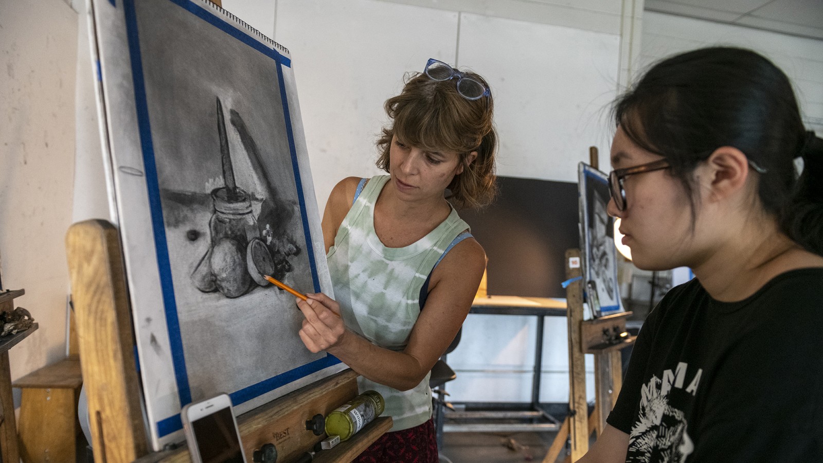 Faculty Gretchen Etlie instructs a student in an art studio.
