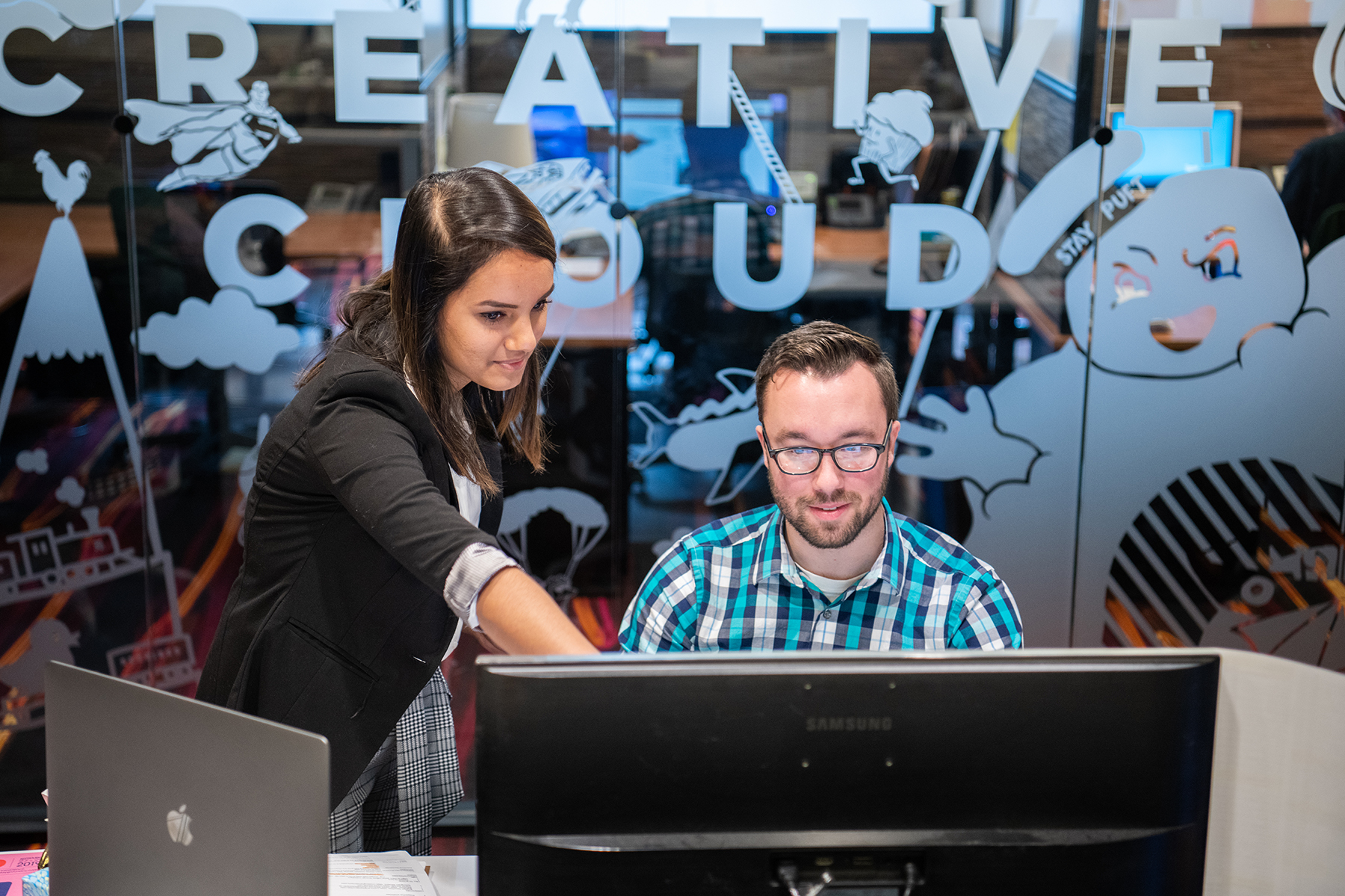 Two people look at a computer screen.