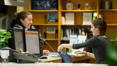 An RIT student employee helping a fellow student in the library.