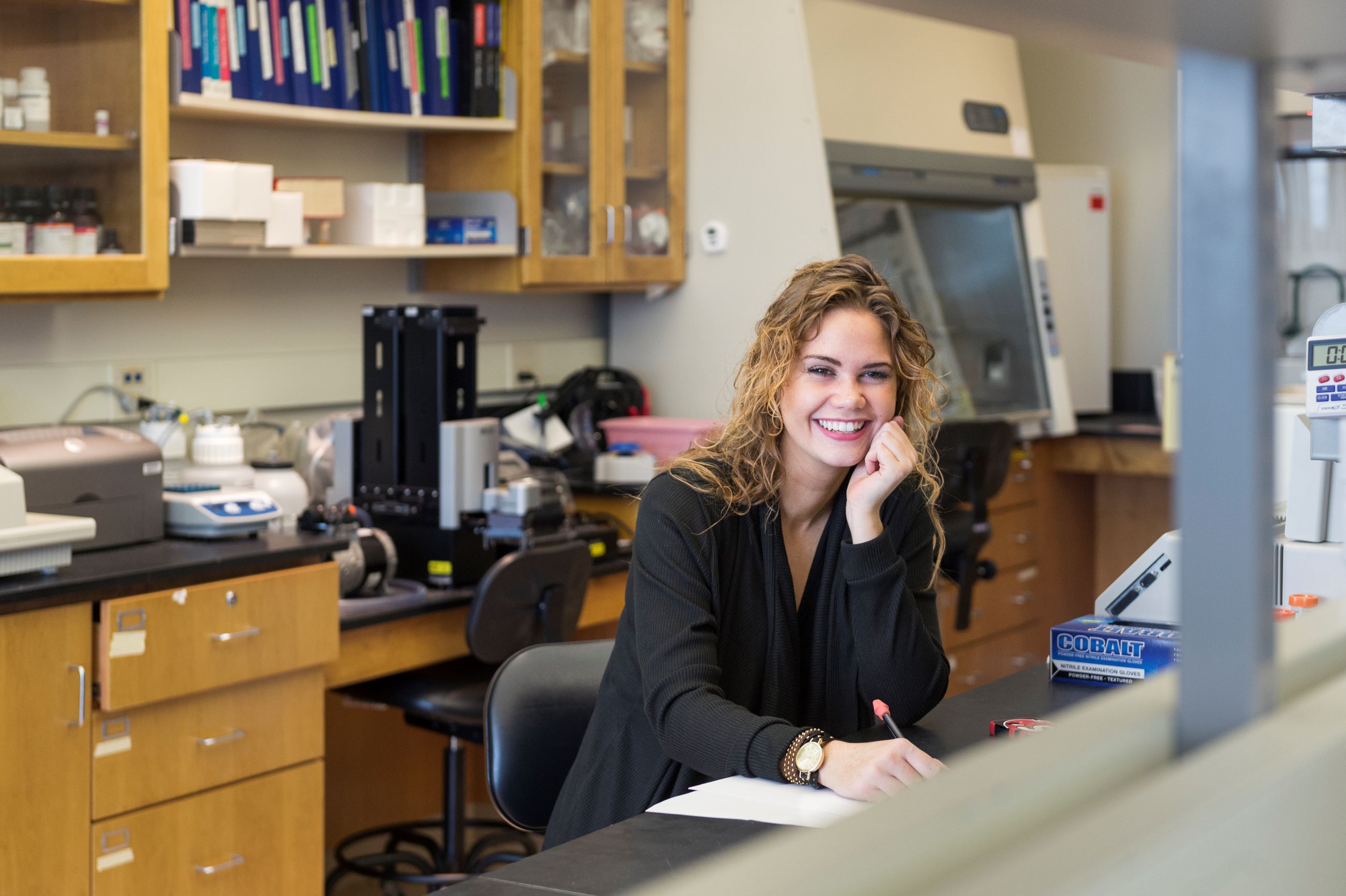 woman smiling and sitting at a lab bench