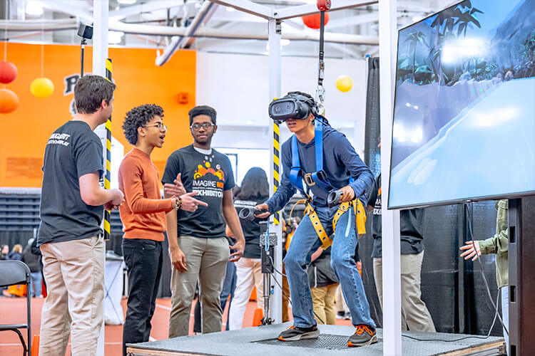 A student tests out a virtual reality exhibit at Imagine RIT while others look on.