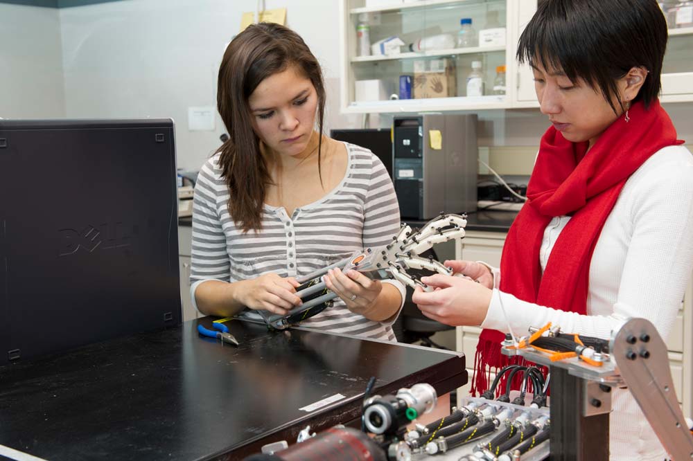 2 people looking at a prosthetic arm  