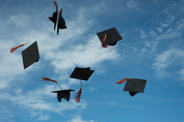 Six graduation hats in the air.