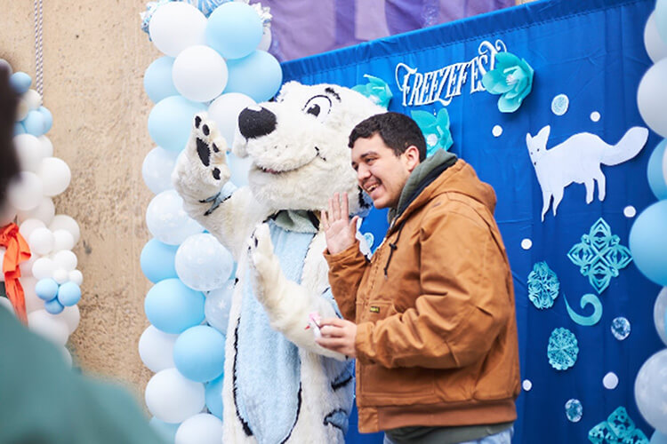 A student poses for a photo with Roarie, the white tiger mascot of FreezeFest.
